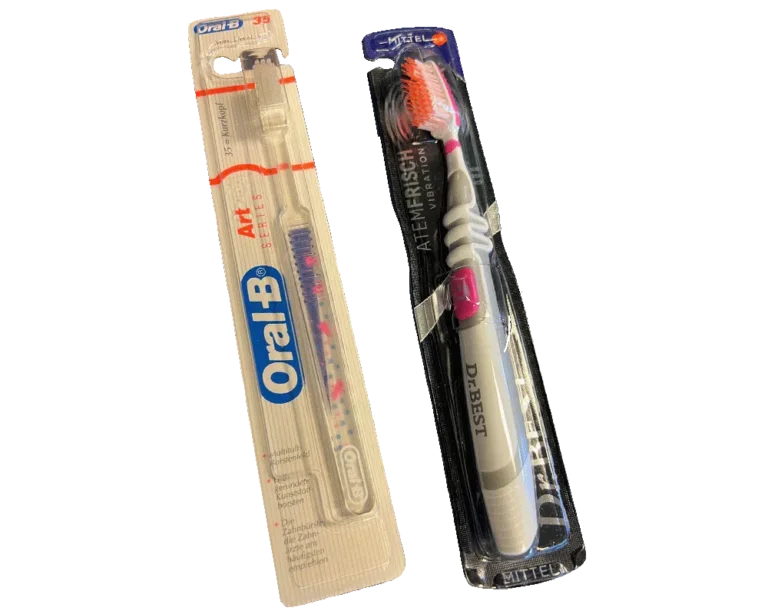Zwei Oral-B-Zahnbürsten im transparenten Sleeve Verpackung mit Skinfolie, weißen Griffen und weichen rosa Borsten auf grauem Hintergrund.