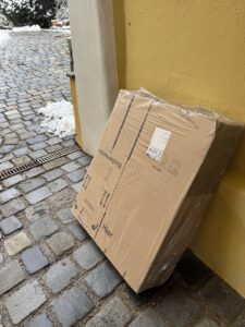 Ein in Plastik verpacktes Paket steht in einem nassen Eingangsbereich